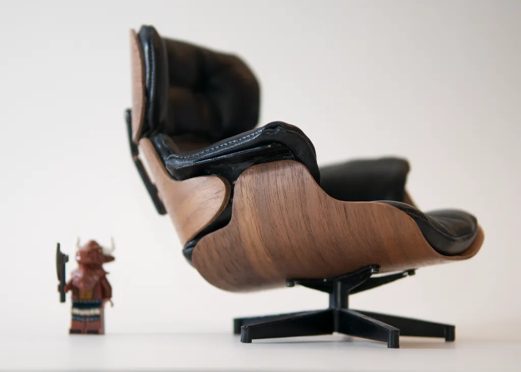 Side view of the scale model with black tufted cushions in walnut-veneer shells on a swivel base, a Lego minifigure standing beside it