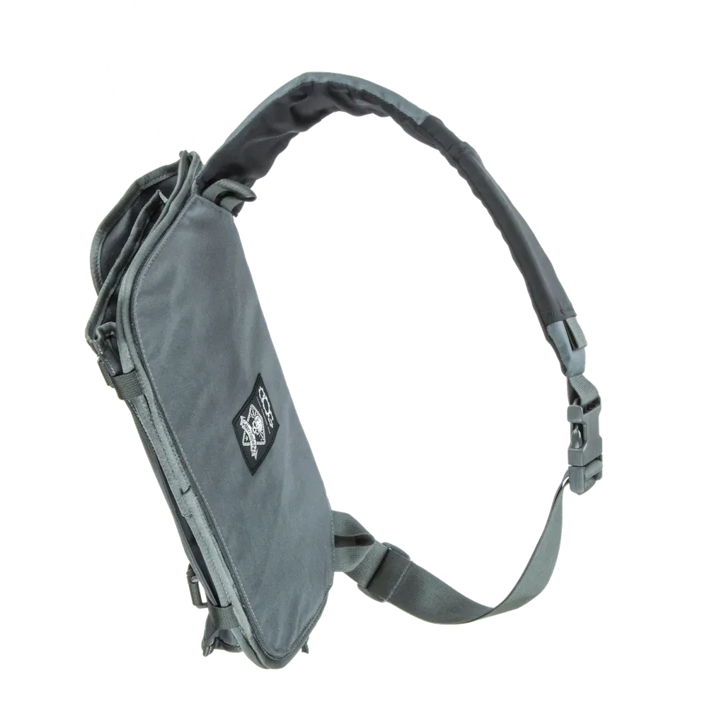 The sling bag in Covert Grey, on a gray background with its shoulder strap looped