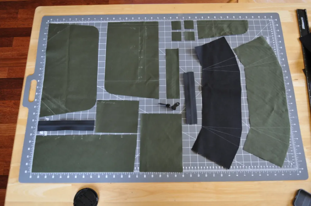 Olive and black fabric pattern pieces laid out on a cutting mat
