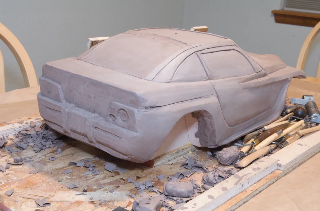 Jeepster model from the front corner, with sculpting tools on the board beside it