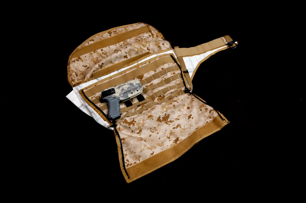 Bag laid open with a digital-camo interior, webbing rows and a handgun held in an internal panel