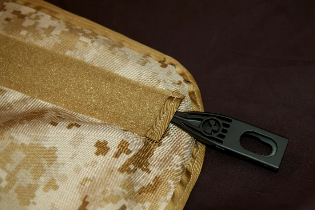 Close-up of a coyote hook-and-loop strap and black pull tab on the digital-camo lining