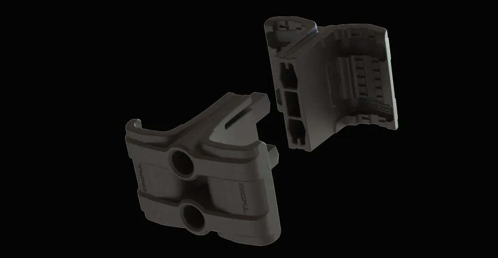 Render of the two black coupler halves separated: the outer half with two bolt holes and Magpul lettering, and the inner half showing grooved channels