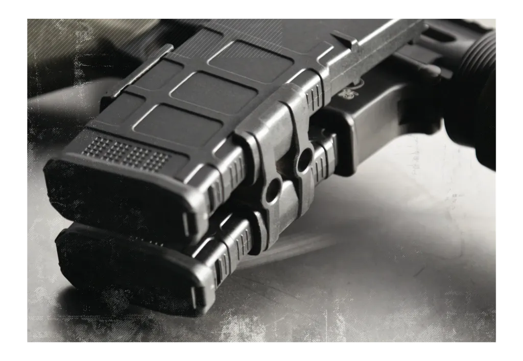 Production Maglink coupling two black PMAGs in a rifle's magwell, photographed on a textured gray surface