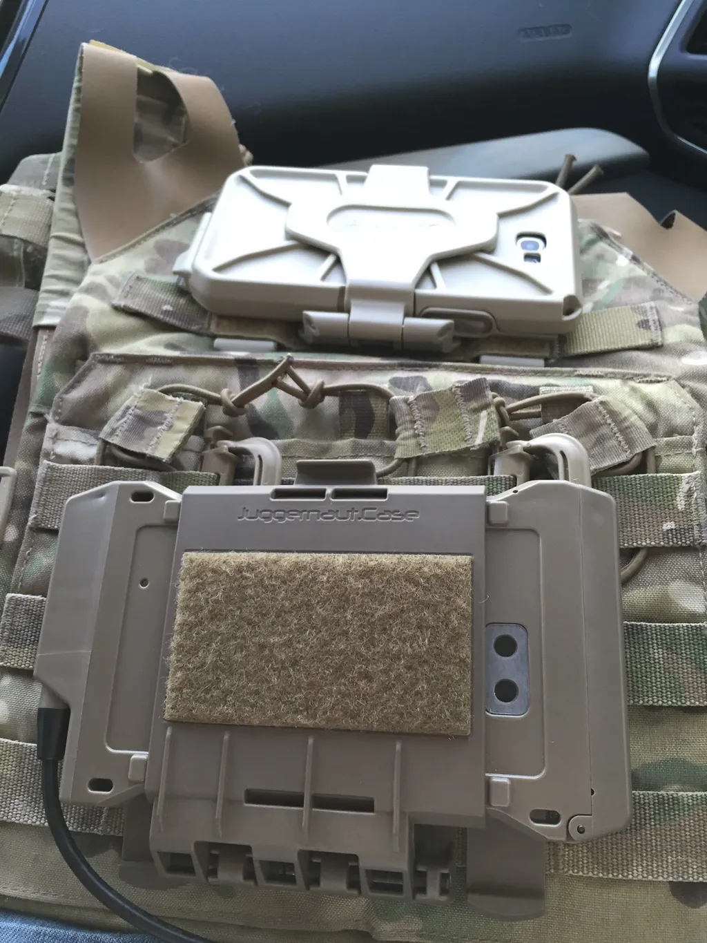 Prototype case holding a phone, mounted on the front of a camouflage plate carrier