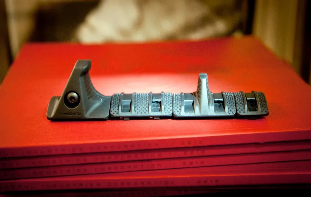 The assembled kit, a hand stop followed by textured covers and the finger index, sitting on a stack of red 2012 Magpul catalogs